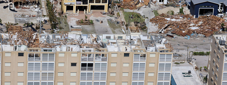 Hurricane-ravaged coastal area with a damaged high-rise and many completely destroyed