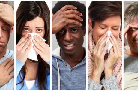 A row of diverse people side-by-side, each showing symptoms of illness like sneezing and headaches.