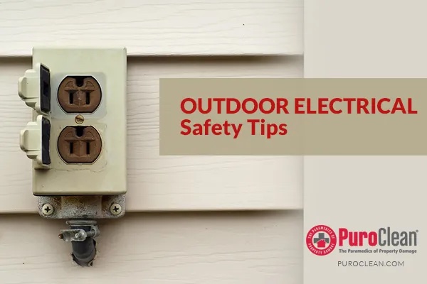 Outdoor electrical outlet with open weather covers on light siding. Text overlay: OUTDOOR ELECTRICAL Safety Tips, PuroClean logo, PUROCLEAN.COM.⁠