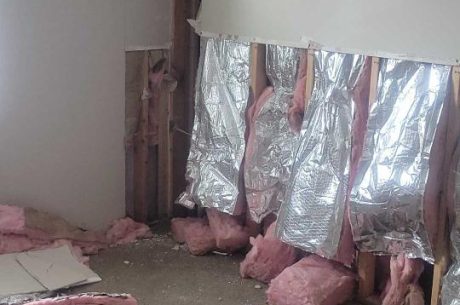 insulation being removed from walls during apartment restoration project.