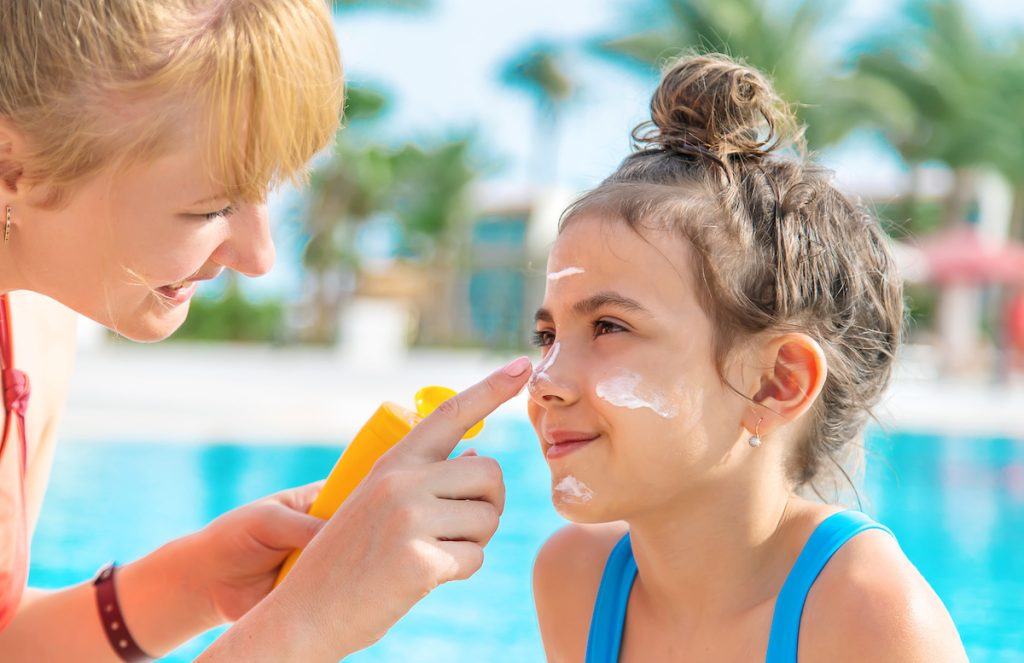 A mother putting on a daughters sun block | Summer Safety