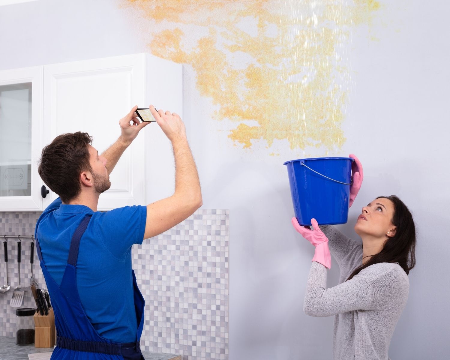 Homeowners catching water from a ceiling leak in buckets