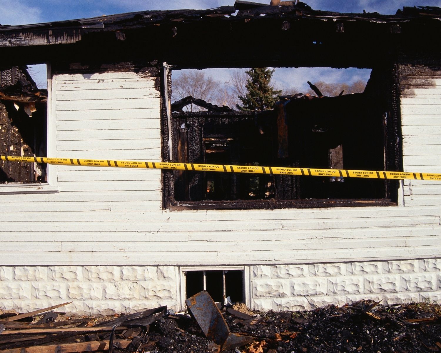 Fire-damaged home with caution tape representing the decision between professional and DIY cleanup