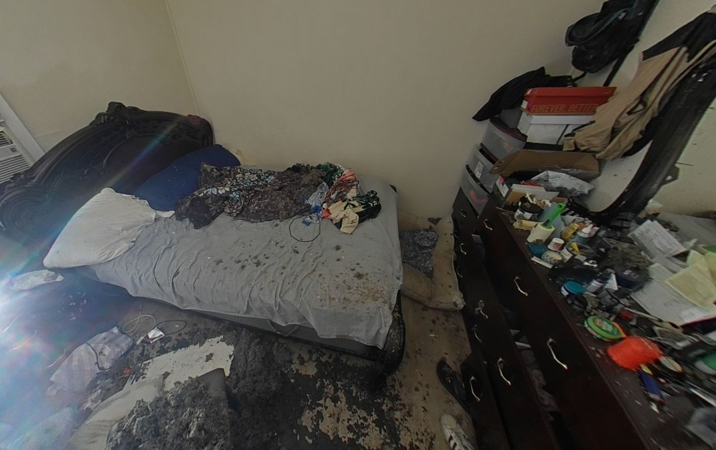 Bedroom with fire damage, charred flooring, and damaged bed