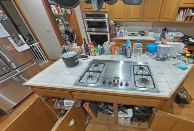 Kitchen island with gas cooktop and open lower cabinets during cleaning