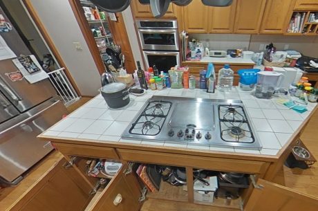 Kitchen island with gas cooktop and open lower cabinets during cleaning