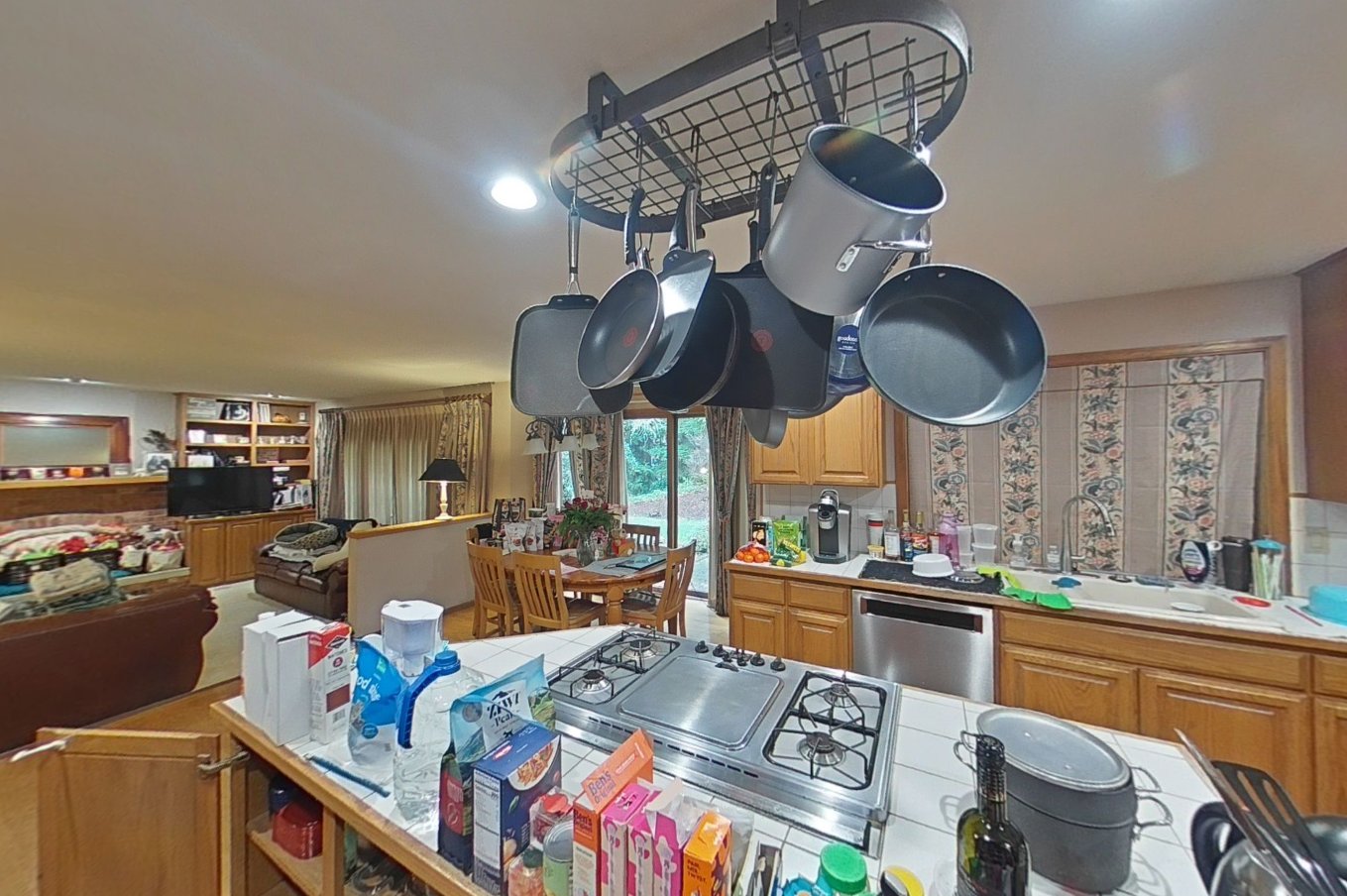 Kitchen overview showing ABC powder residue on hanging pots, gas cooktop, and island surfaces during cleanup
