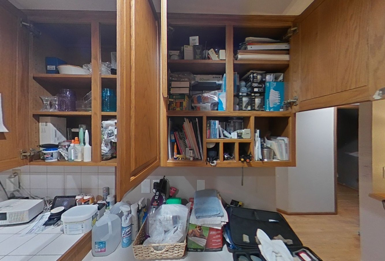 Upper kitchen cabinets open with contents being cleaned in place by PuroClean technicians