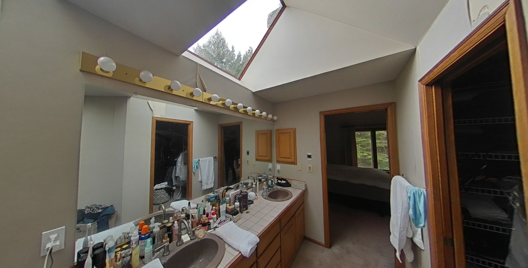 Close-up of master bathroom dual vanity and countertop being cleaned under skylight