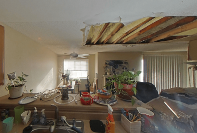 Kitchen-facing view of the damaged ceiling with exposed joists and insulation after the explosion above.