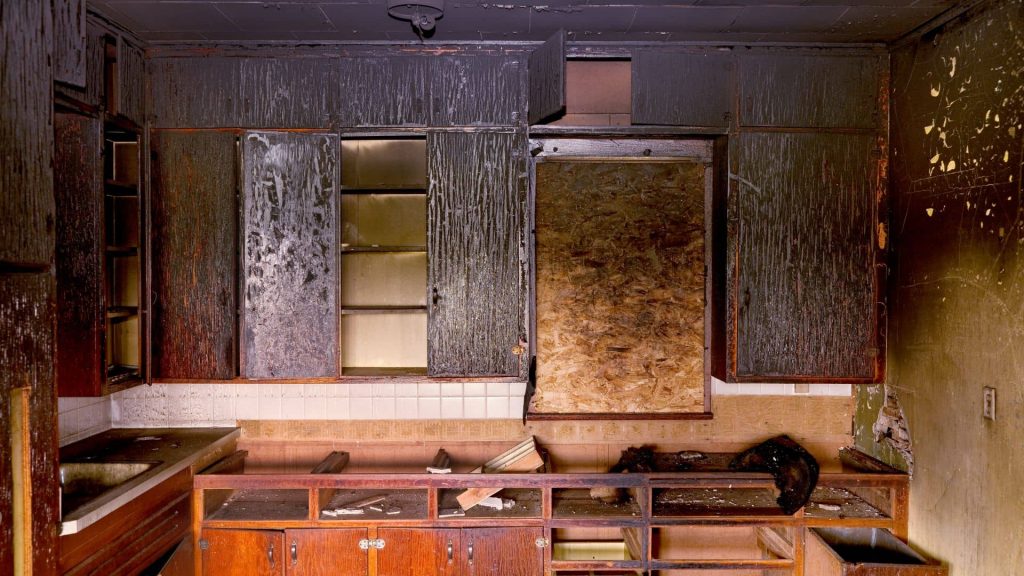 restoration technician using specialized soot cleanup equipment inside a smoke-damaged room
