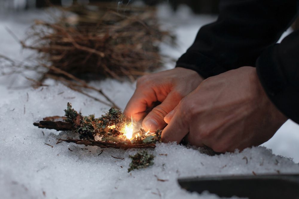 Man lights fire in snow. Winter fire safety tips.