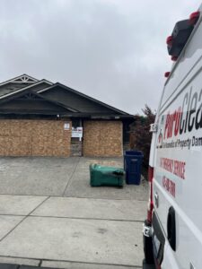 Boarded up garage exterior of a fire damaged home in Everett WA with a PuroClean response van parked out front