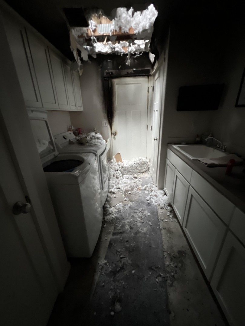 Fire breached laundry room ceiling showing how flames spread from the attached garage