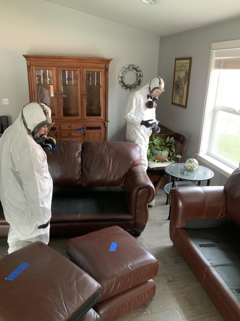 Restoration technicians in protective equipment assessing smoke damaged living room contents