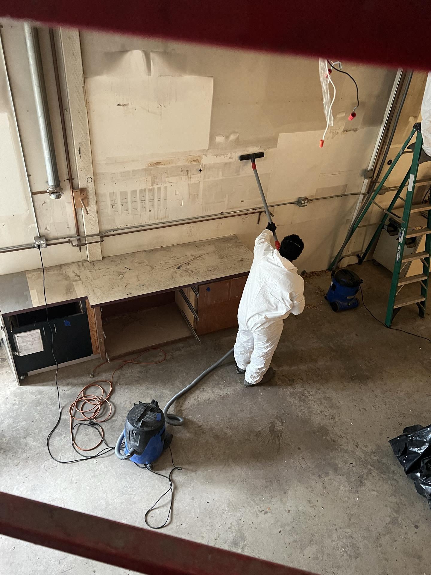 Restoration technician cleaning the concrete shop floor after a commercial structure fire in Seattle WA