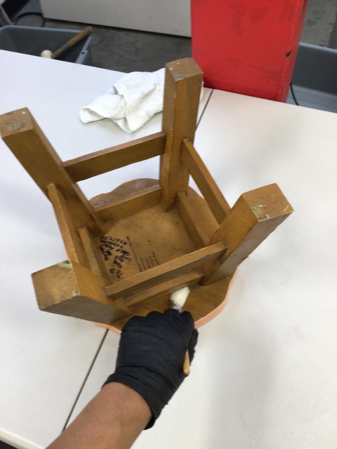Restoration technician using a detail brush to clean soot from the joints of a wooden stool after a house fire