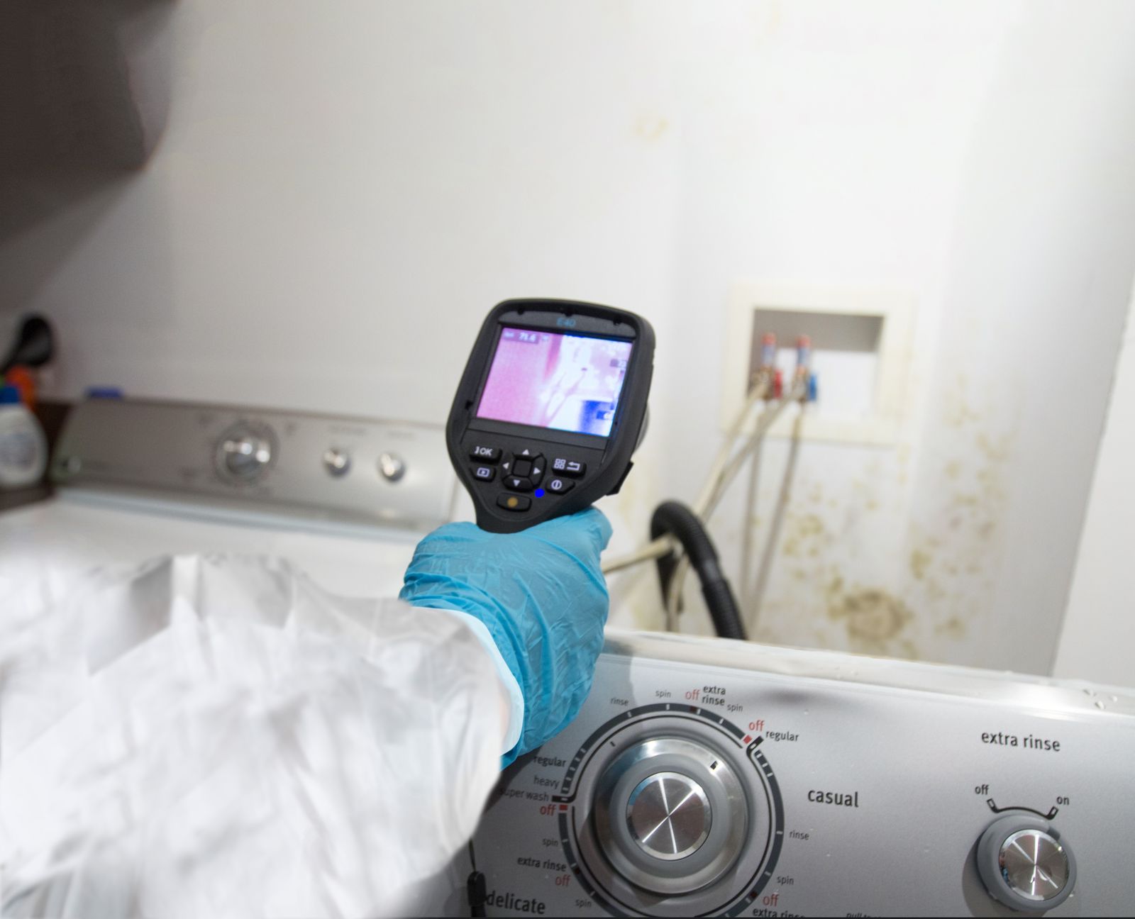 person wearing protective gear holding an infrared camera to look at mold