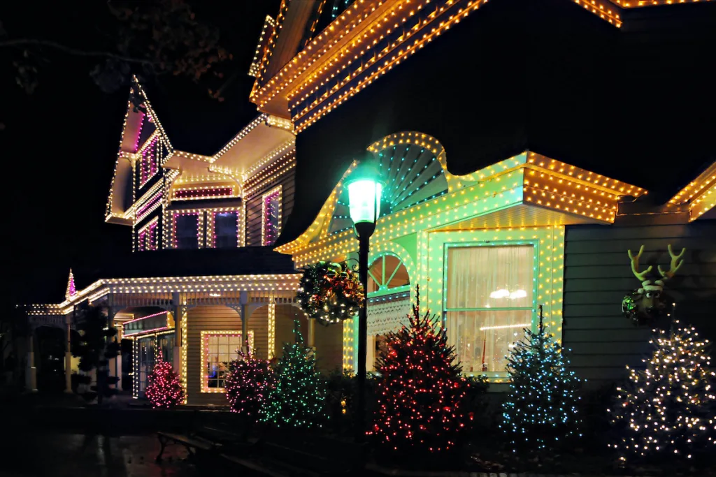 House brightly decorated with colorful holiday lights and illuminated trees at night