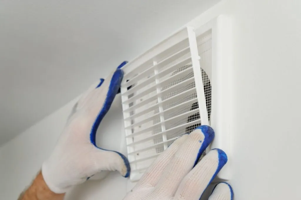 technician installing grill on a wall vent