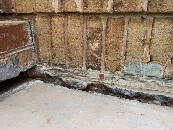 A basement with water-damaged concrete and damaged walls