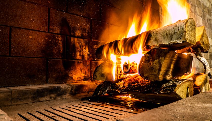 A fire lit on a log in a fireplace