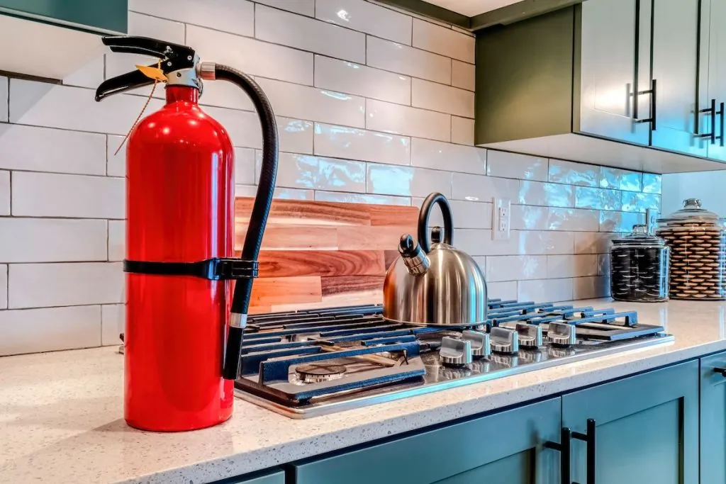 A fire extinguisher next to an indoor stove.