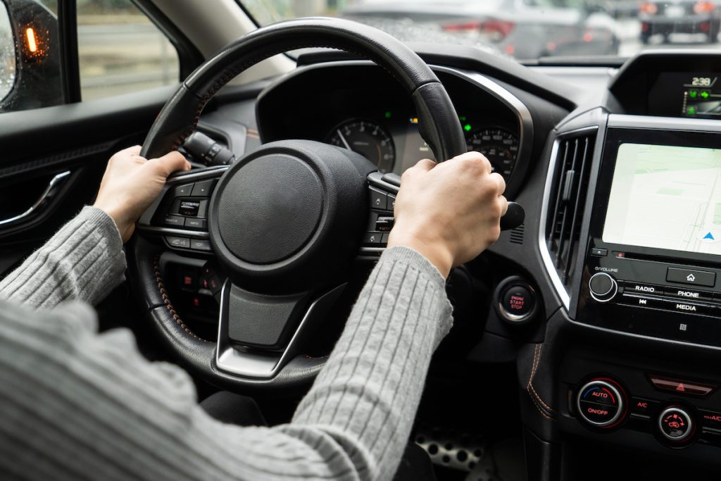 A person holding the steering wheel while driving. 