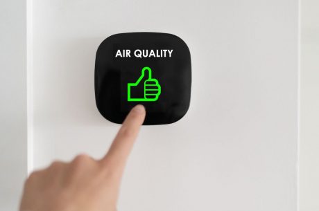 hand adjusting a thermostat for air quality
