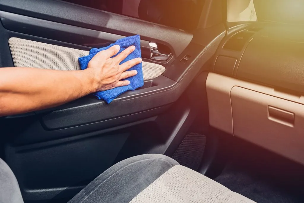 Worker man cleaning dust interior by cloth microfiber inside car after wash