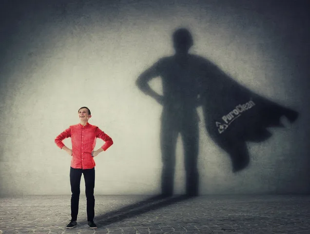 PuroClean superhero with a cape in the shadows