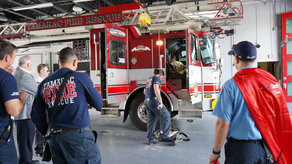 The Tamarac Fire Rescue watches as a crew member demonstrates how to put on gear quickly.