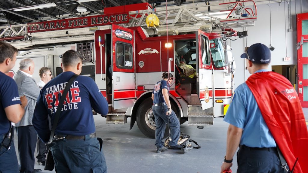 The Tamarac Fire Rescue watches as a crew member demonstrates how to put on gear quickly.