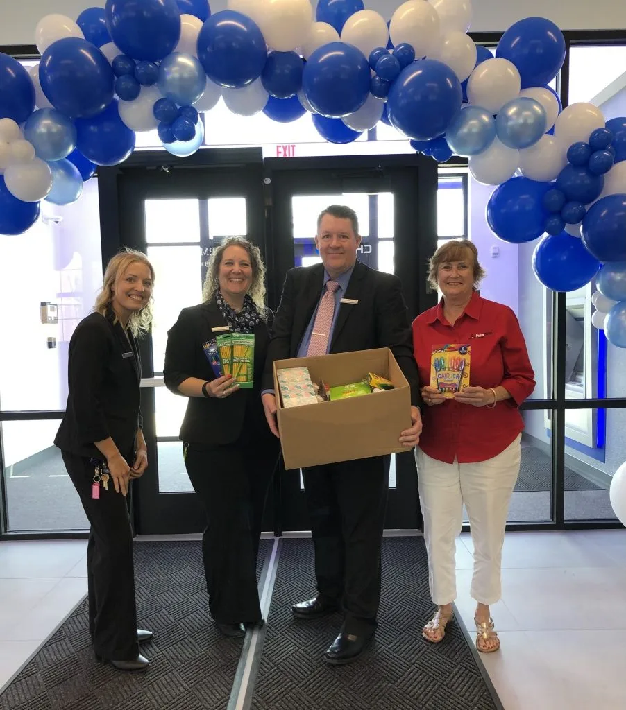 Teachers under a balloon arch while receiving school supplies and a check from PuroClean Adopt A Classroom Campaign