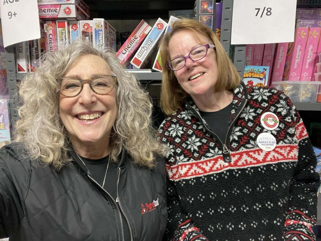 2 ladies from PuroClean in Kingston, NY in front of games and puzzle donations
