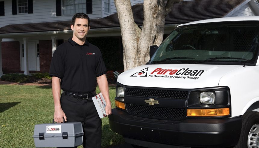 PuroClean technician in front of PuroClean vehicle at residential property.