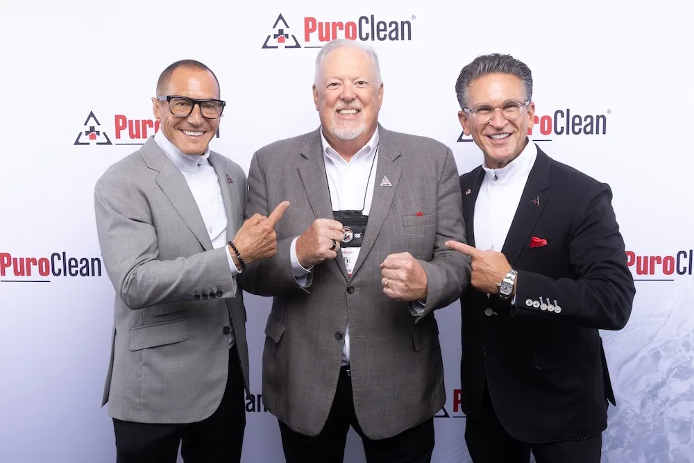 PuroClean's Executive Leadership team in front of a PuroClean banner