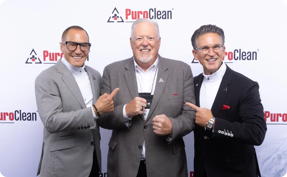 PuroClean's Executive Leadership team in front of a PuroClean banner